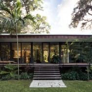 Floor-to-ceiling windows expand the home’s open, airy ambiance and garden vistas while a variety of woods