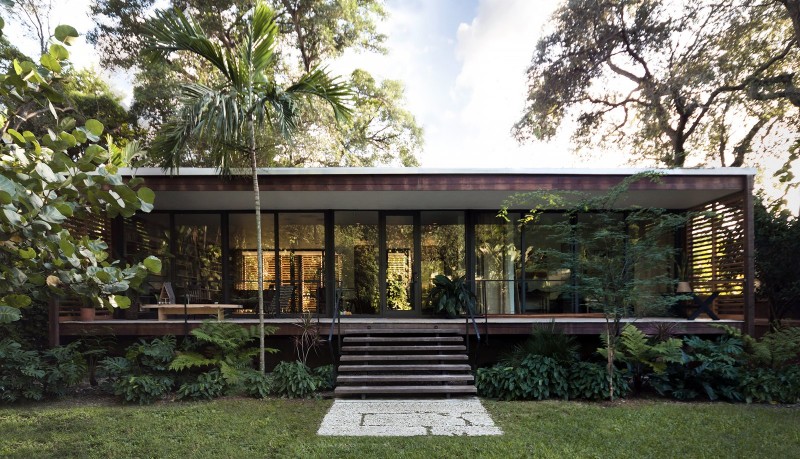 Floor-to-ceiling windows expand the home’s open, airy ambiance and garden vistas while a variety of woods